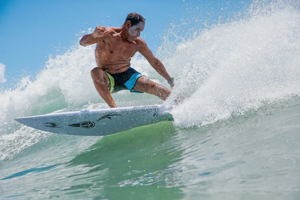 Fábio Silva executa uma manobra de surfe e levanta água com a prancha.
